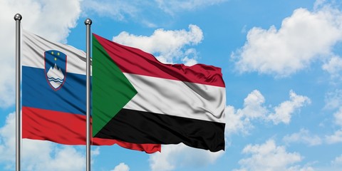 Slovenia and Sudan flag waving in the wind against white cloudy blue sky together. Diplomacy concept, international relations.