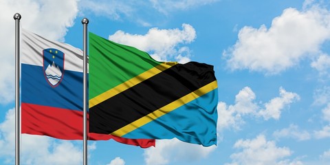 Slovenia and Tanzania flag waving in the wind against white cloudy blue sky together. Diplomacy concept, international relations.