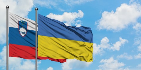 Slovenia and Ukraine flag waving in the wind against white cloudy blue sky together. Diplomacy concept, international relations.