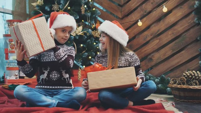 Full-body timelapse video of cute children sitting in lotos position with Christmas presents, finding out what is inside.