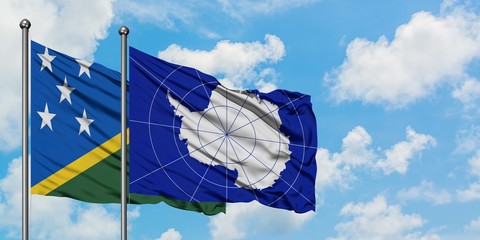 Solomon Islands and Antarctica flag waving in the wind against white cloudy blue sky together. Diplomacy concept, international relations.