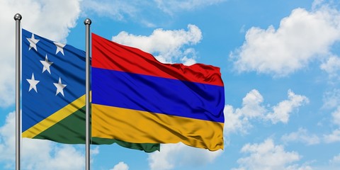 Solomon Islands and Armenia flag waving in the wind against white cloudy blue sky together....