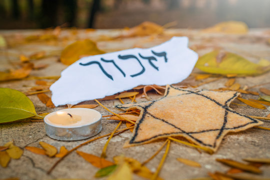 Hebrew inscription "remember", cande and Star of David on autumn leaves in the park