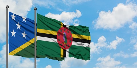 Solomon Islands and Dominica flag waving in the wind against white cloudy blue sky together. Diplomacy concept, international relations.