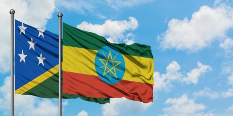 Solomon Islands and Ethiopia flag waving in the wind against white cloudy blue sky together....