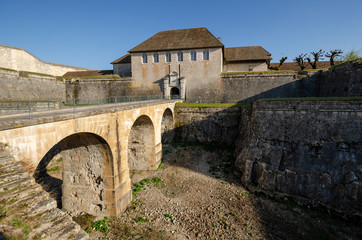 View of the old citadel in the city of Besancon, France. There is a bridge across a deep moat and entrance gate. Scenery. Background.