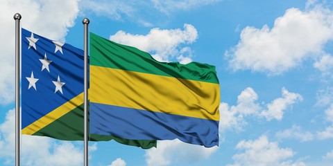 Solomon Islands and Gabon flag waving in the wind against white cloudy blue sky together. Diplomacy concept, international relations.