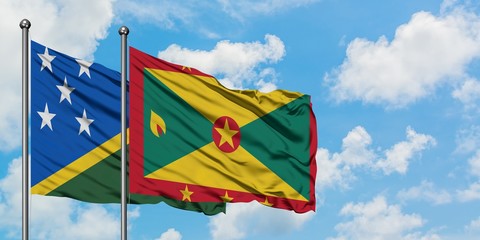 Solomon Islands and Grenada flag waving in the wind against white cloudy blue sky together. Diplomacy concept, international relations.
