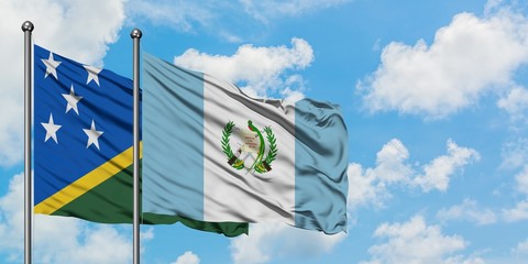 Solomon Islands and Guatemala flag waving in the wind against white cloudy blue sky together....