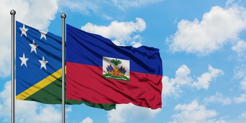 Solomon Islands and Haiti flag waving in the wind against white cloudy blue sky together. Diplomacy...