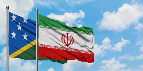 Solomon Islands and Iran flag waving in the wind against white cloudy blue sky together. Diplomacy concept, international relations.