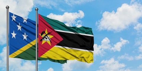Solomon Islands and Mozambique flag waving in the wind against white cloudy blue sky together. Diplomacy concept, international relations.