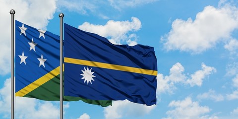 Solomon Islands and Nauru flag waving in the wind against white cloudy blue sky together. Diplomacy concept, international relations.