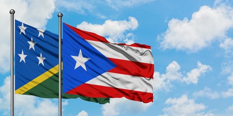 Solomon Islands and Puerto Rico flag waving in the wind against white cloudy blue sky together. Diplomacy concept, international relations.