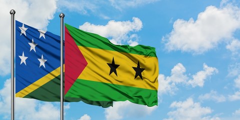 Solomon Islands and Sao Tome And Principe flag waving in the wind against white cloudy blue sky together. Diplomacy concept, international relations.