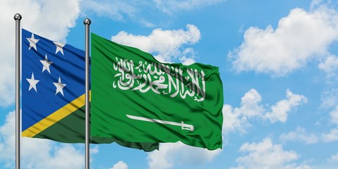 Solomon Islands and Saudi Arabia flag waving in the wind against white cloudy blue sky together....