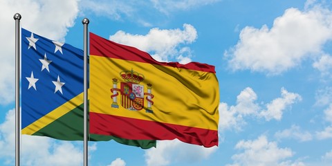 Solomon Islands and Spain flag waving in the wind against white cloudy blue sky together. Diplomacy concept, international relations.
