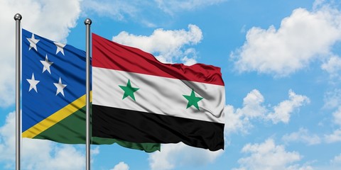 Solomon Islands and Syria flag waving in the wind against white cloudy blue sky together. Diplomacy...