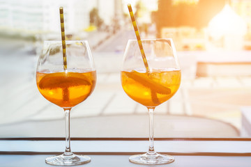 Aperol alcoholic drink with ice cubes in a glass and an eco-friendly cardboard tube. Popular cocktail, bar menu, orange liquid.