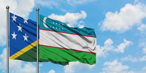 Solomon Islands and Uzbekistan flag waving in the wind against white cloudy blue sky together....