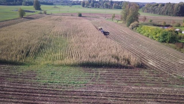 Aerial of a harvesting machine operating in a small corn field, TRACKING SHOT LEFT TO RIGHT