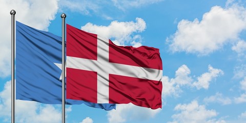 Somalia and Denmark flag waving in the wind against white cloudy blue sky together. Diplomacy concept, international relations.