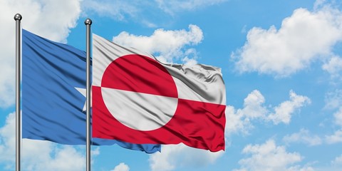 Somalia and Greenland flag waving in the wind against white cloudy blue sky together. Diplomacy concept, international relations.