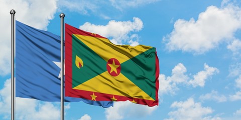 Somalia and Grenada flag waving in the wind against white cloudy blue sky together. Diplomacy concept, international relations.
