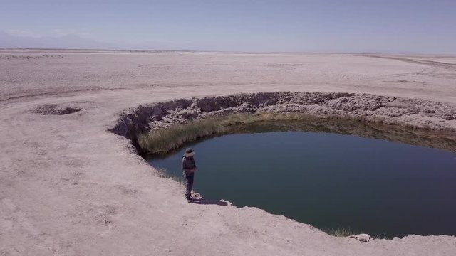 Aerial view of geologist walking around the edge of the eyes of the salt flats, San Pedro de Atacama, Chile. 4k