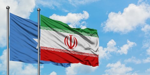 Somalia and Iran flag waving in the wind against white cloudy blue sky together. Diplomacy concept, international relations.