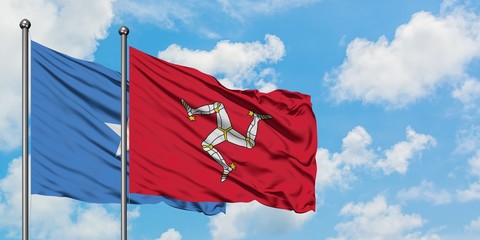 Somalia and Isle Of Man flag waving in the wind against white cloudy blue sky together. Diplomacy concept, international relations.