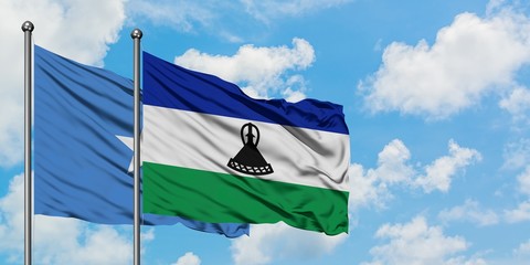 Somalia and Lesotho flag waving in the wind against white cloudy blue sky together. Diplomacy...