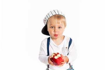 Baby boy eating apple and smiling in the studio isolated on white background