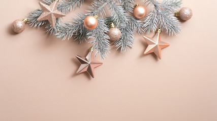 Christmas copper decorations and fir tree branch on beige background. Glamour fashion style...