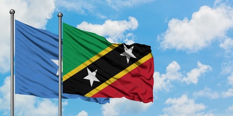 Somalia and Saint Kitts And Nevis flag waving in the wind against white cloudy blue sky together. Diplomacy concept, international relations.