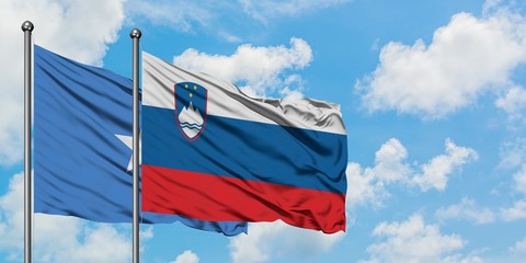 Somalia and Slovenia flag waving in the wind against white cloudy blue sky together. Diplomacy concept, international relations.