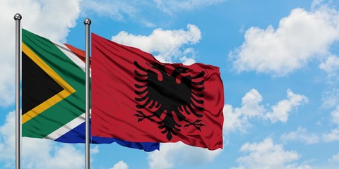 South Africa and Albania flag waving in the wind against white cloudy blue sky together. Diplomacy concept, international relations.