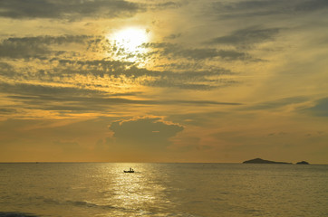A picturesque tropical grey coloured nimbostratus clouds coastal sunrise seascape in a yellow sky. Thailand.