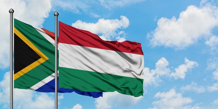 South Africa and Hungary flag waving in the wind against white cloudy blue sky together. Diplomacy concept, international relations.