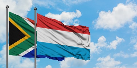 South Africa and Luxembourg flag waving in the wind against white cloudy blue sky together. Diplomacy concept, international relations.