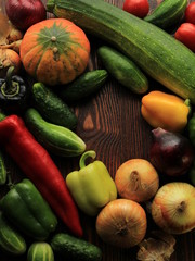 fresh vegetables in a basket on a wooden table. cucumbers, zucchini, onions, bell peppers, pumpkin collected in a basket. 