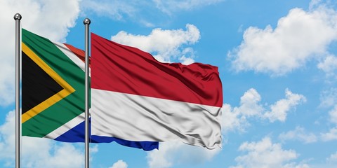 South Africa and Monaco flag waving in the wind against white cloudy blue sky together. Diplomacy concept, international relations.