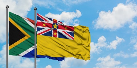 South Africa and Niue flag waving in the wind against white cloudy blue sky together. Diplomacy concept, international relations.