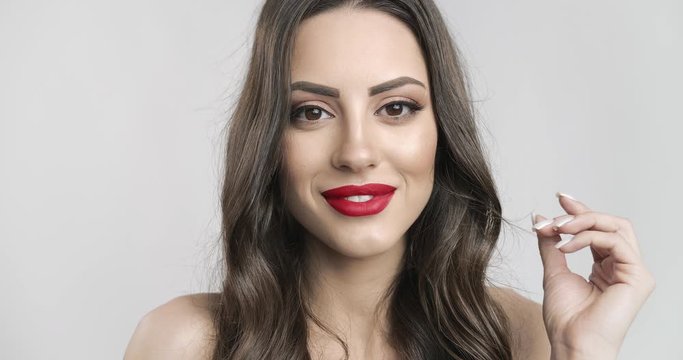 Portrait of gorgeous brunette woman with red lipstick makeup smiling to camera isolated on white background, face closeup
