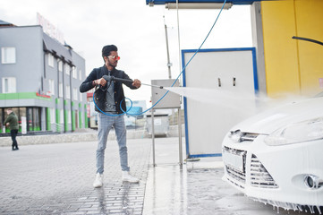 South asian man or indian male washing his white transportation on car wash.