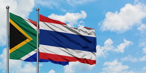 South Africa and Thailand flag waving in the wind against white cloudy blue sky together. Diplomacy...