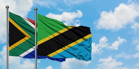 South Africa and Tanzania flag waving in the wind against white cloudy blue sky together. Diplomacy concept, international relations.