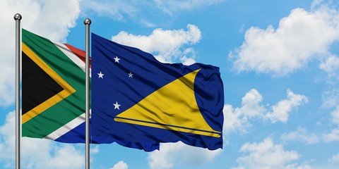 South Africa and Tokelau flag waving in the wind against white cloudy blue sky together. Diplomacy concept, international relations.