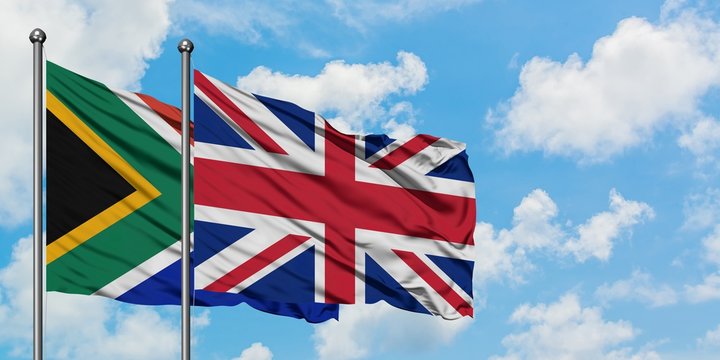 South Africa and United Kingdom flag waving in the wind against white cloudy blue sky together. Diplomacy concept, international relations.