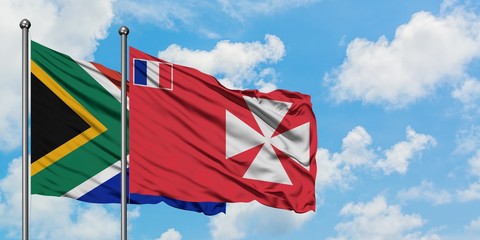 South Africa and Wallis And Futuna flag waving in the wind against white cloudy blue sky together....